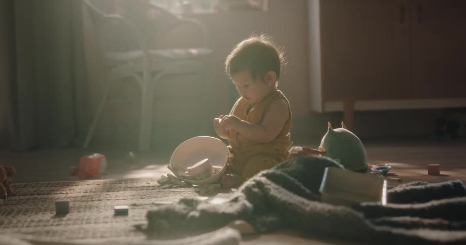 A very young child sits and plays with several blocks while sitting on the floor