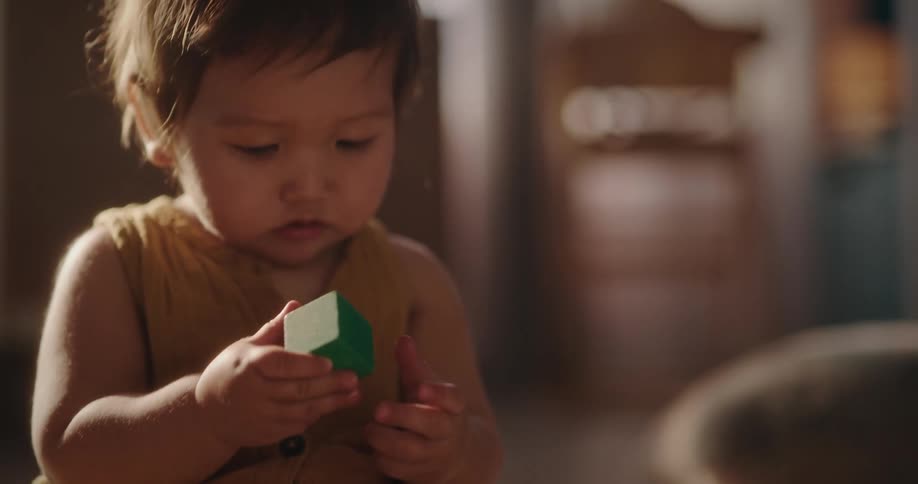 Baby holding a toy observing then letting go of the toy and starting to crawl