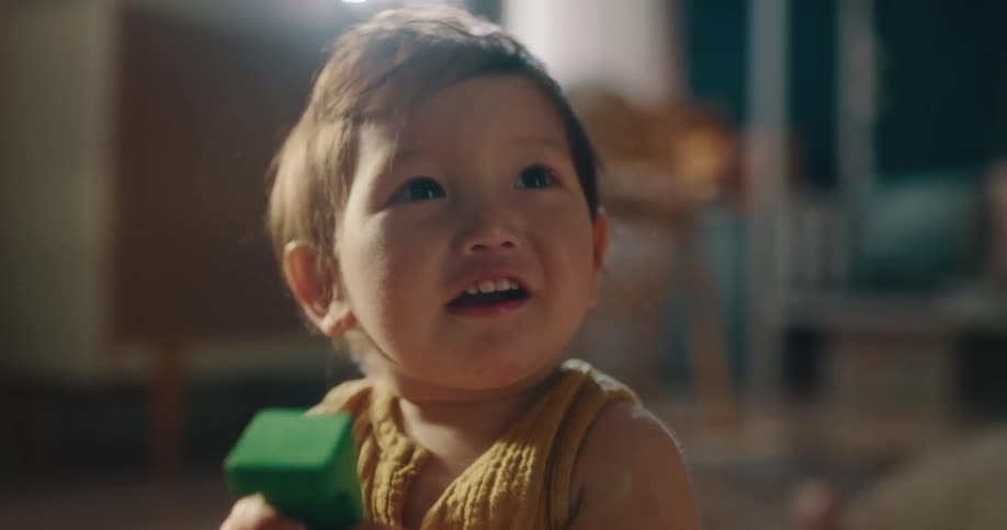 Happy baby sitting on floor drops toy to clap