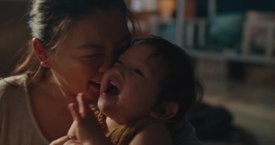 Mother holding her baby and playing both smiling and having fun
