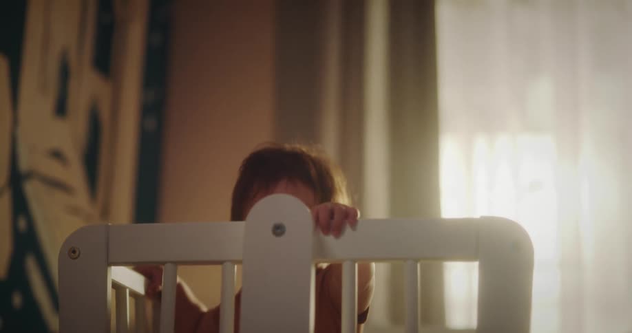 Toddler stands up on a crib in the bedroom