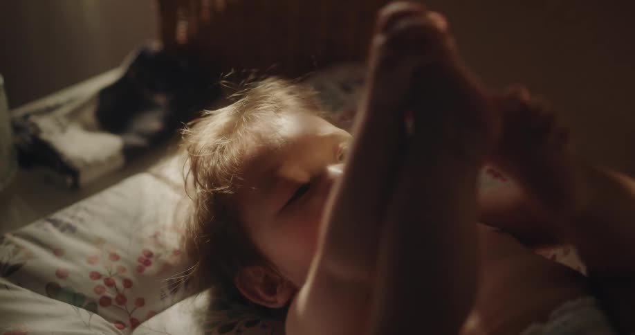 Hands of a person playing with a smiling baby