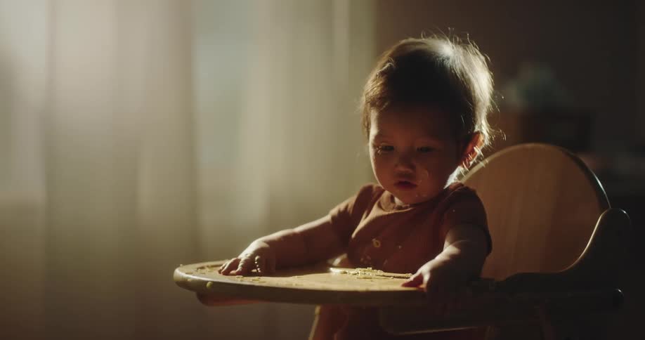 Toddler sits in high chair and bangs hands on tray