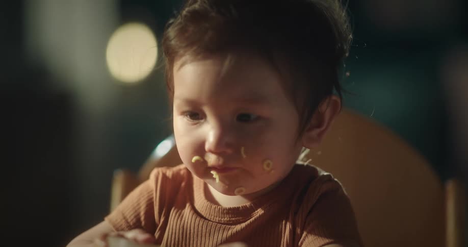 Baby sitting and eating food with her hands