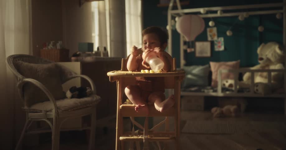 Toddler eats and drinks while sitting in high chair