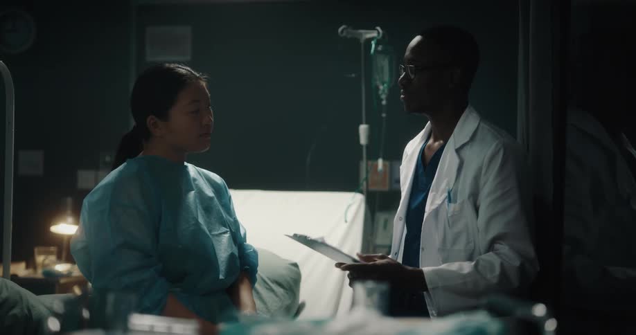 Doctor talks to patient sitting on hospital bed before leaving