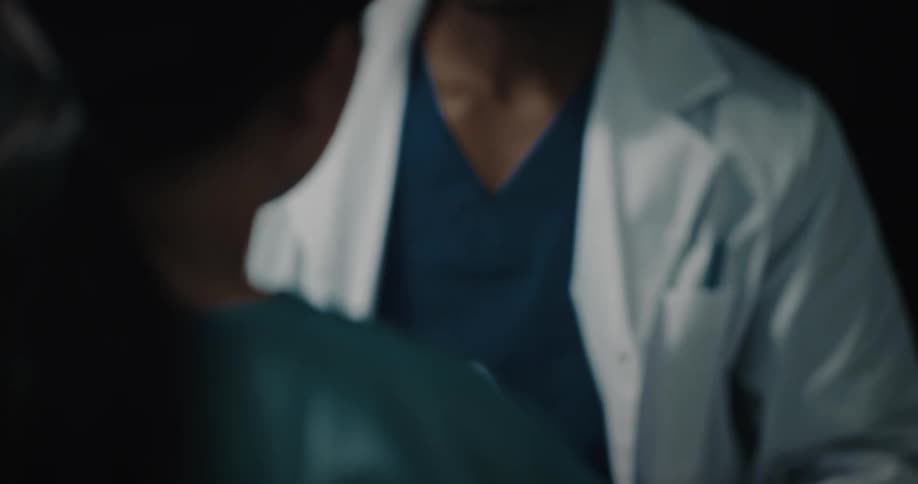 Doctor wearing a white lab coat reviewing a medical chart and having a serious conversation with a nurse