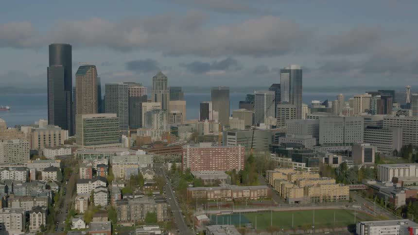 There are heavy clouds above the water near this large city