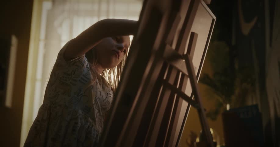 A girl child writing on a art board inside the room