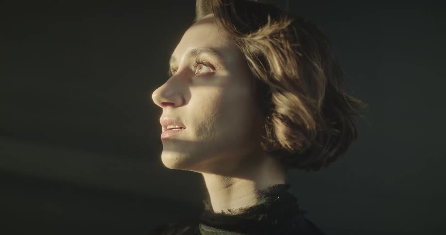 A woman opens her eyes when a light illuminates her face and the wind moves her hair