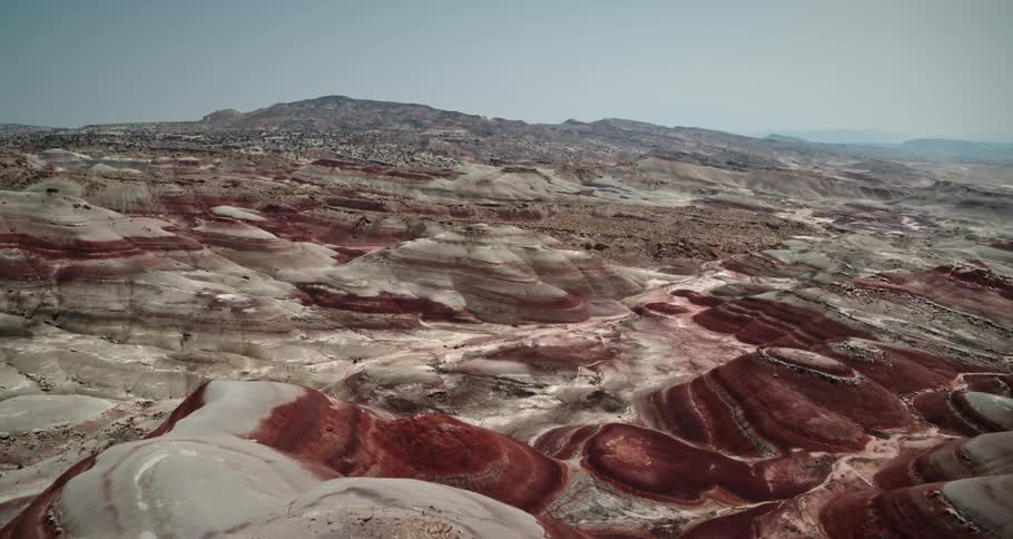 Rock layered mountains stretch across the desert with mountains in the distance