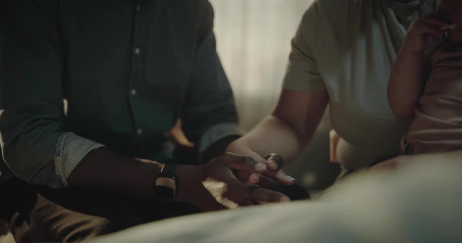 A father and mother wearing a face mask holding hands while carrying their baby in the hospital
