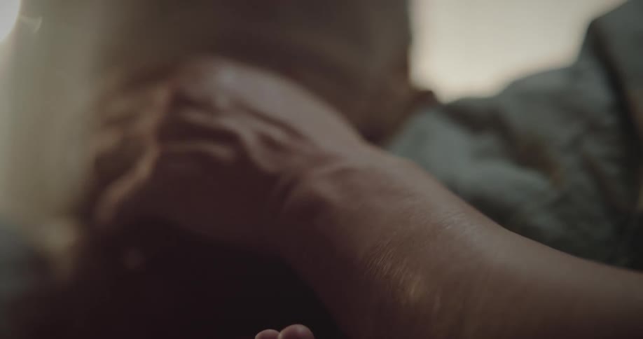 Close up of a baby sitting on top of a person who is lying down
