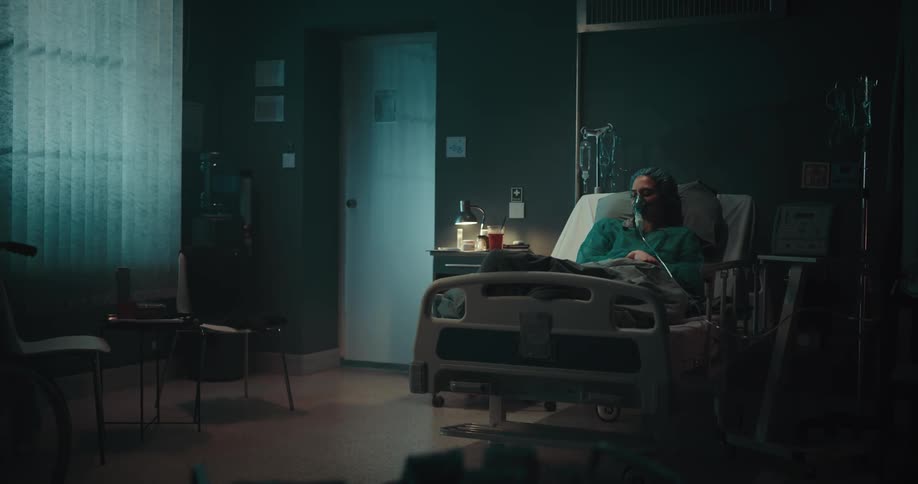 A woman lays in a hospital bed surrounded by medical equipment