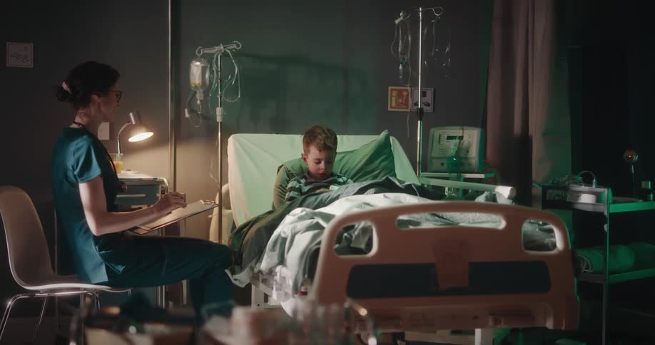 Nurse checks on a boy resting in a hospital bed
