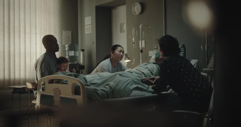 Family sitting around a patient who is sleeping in a hospital room