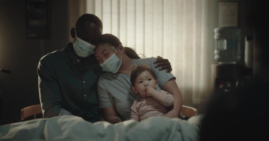A family caring for a man who is intubated in a hospital bed