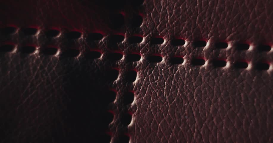 Two parallel rows of holes form cross on textured leather surface
