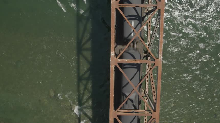 Overhead view of oil train on a river bridge