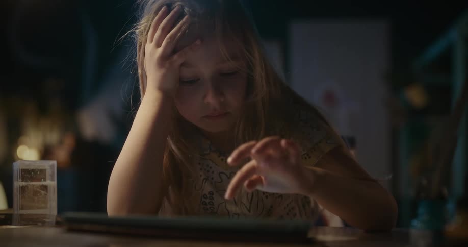 A young girl getting frustrated while tapping on a tablet computer