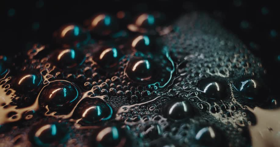 A dark liquid has a large number of bubbles floating on its surface