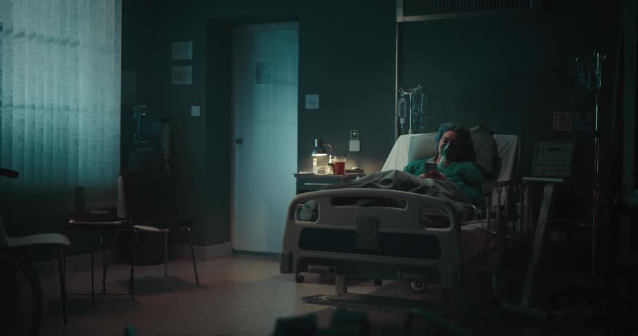 Patient lying in a hospital bed with an oxygen mask using a mobile phone