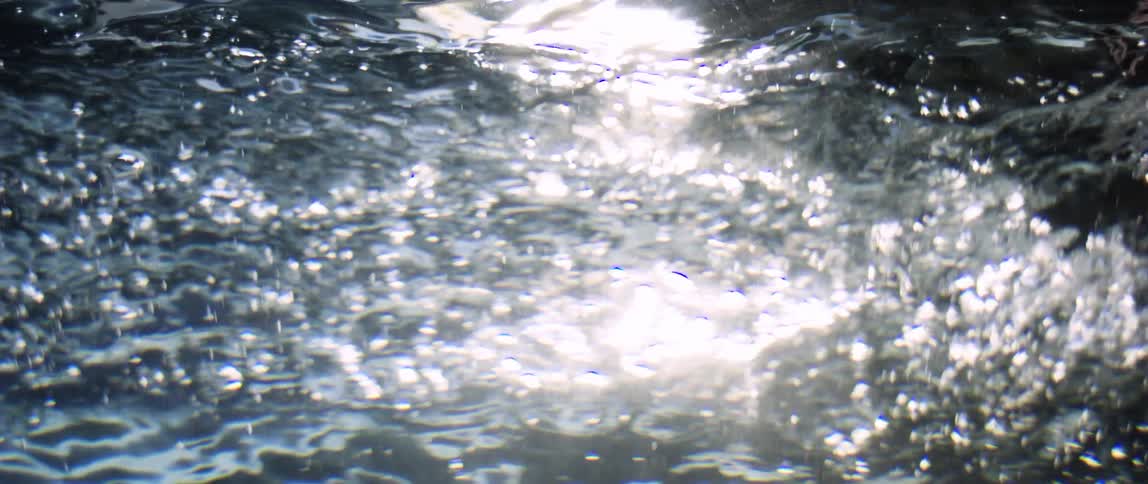 Person runs their hand through water creating bubbles