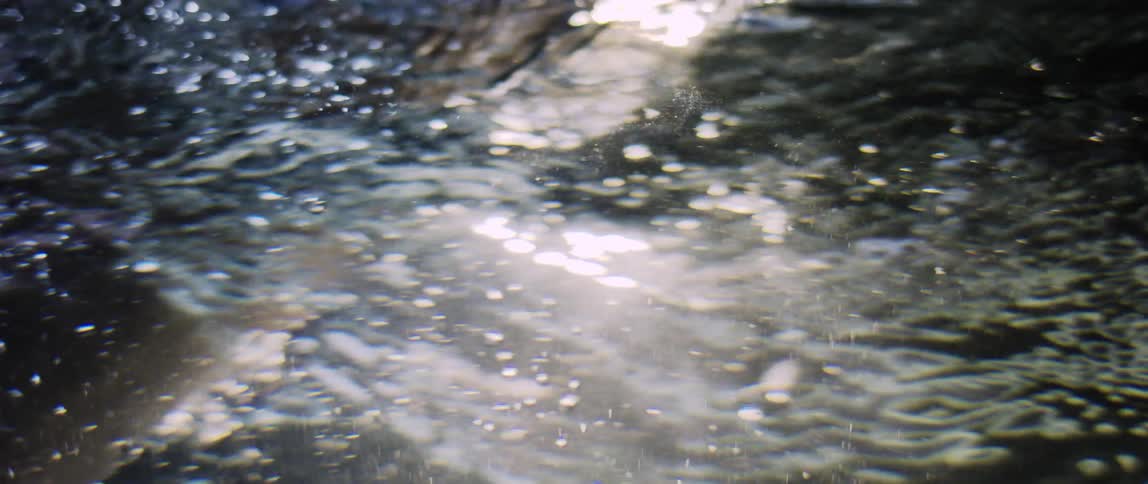 Hand of a person passing through the water and forming small bubbles