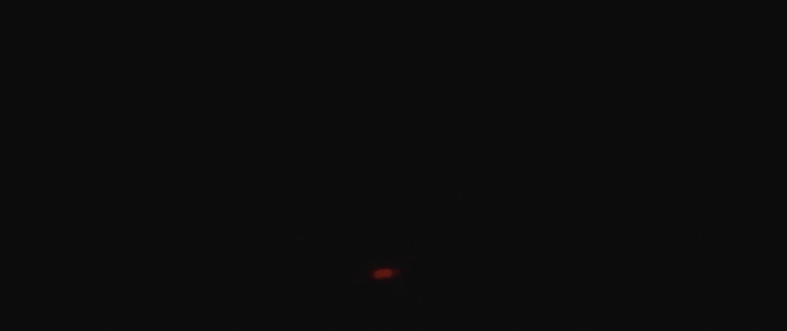 The flame of a match glows in the darkness as smoke rises