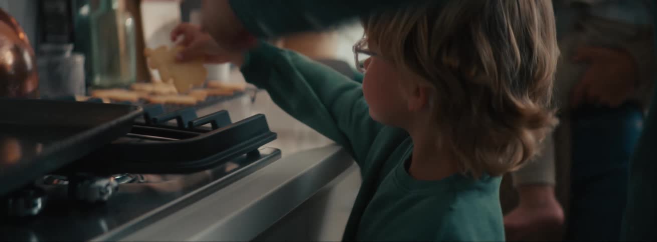 A little blond boy with glasses has a meal in his hand and puts it on the table