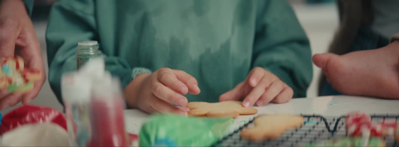 Portrait of a boy in the kitchen with his parents grabbing a christmas cookie