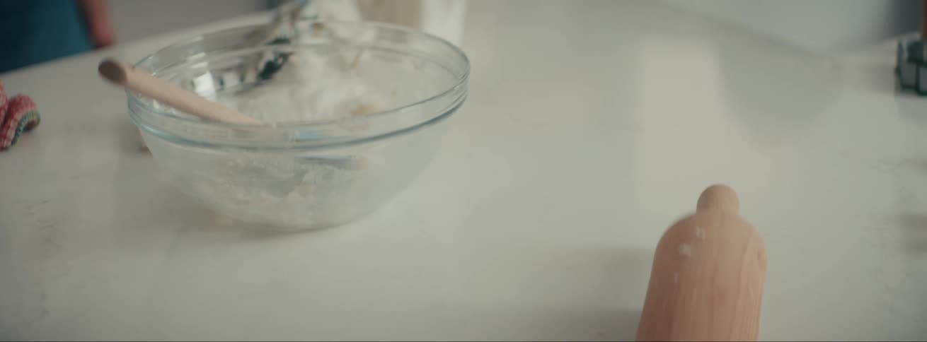 Bowl with a spatula and a wooden rolling pin on top of a white kitchen counter