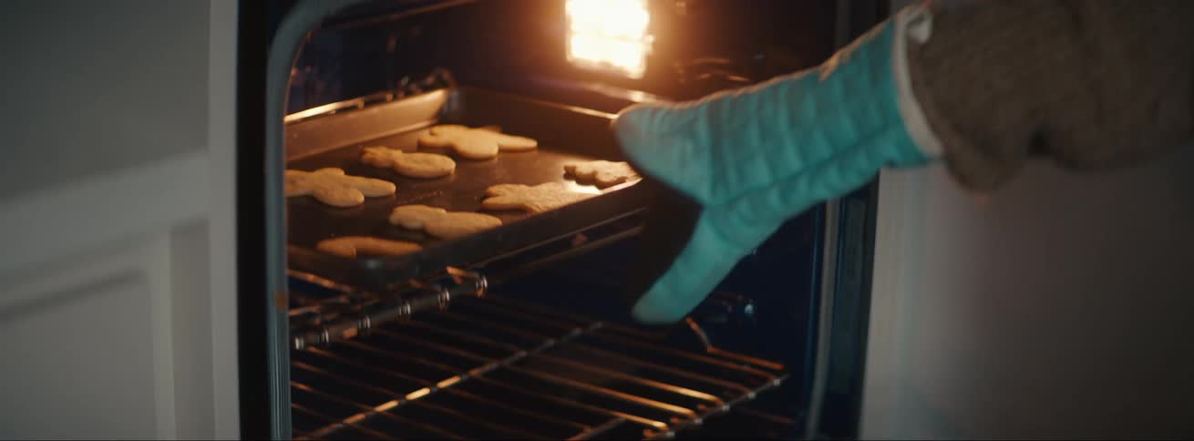 Mother holding child removes cookies from oven