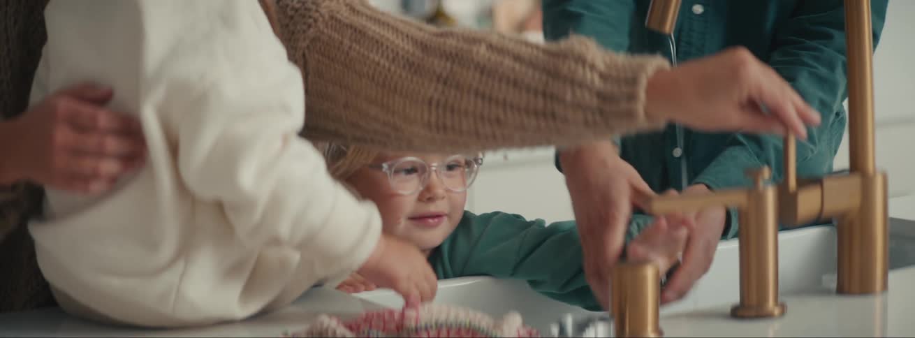 Child washing hands with their parents and sibling nearby