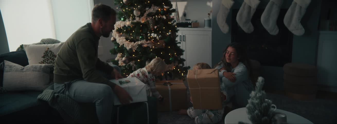 Family in the living room with a christmas tree and closed presents ready to be opened