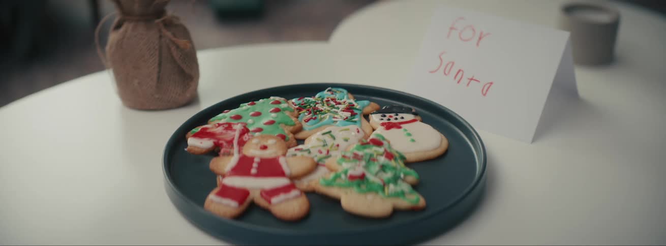 A table with a plate of christmas cookies and a white card beside it