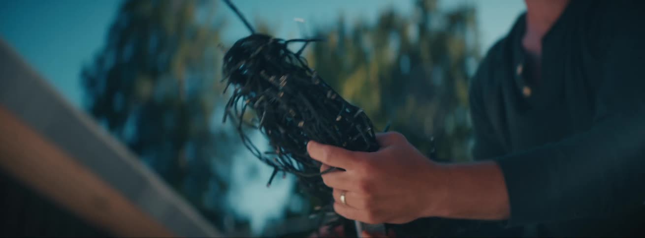 Man untangles and hangs string lights outdoors