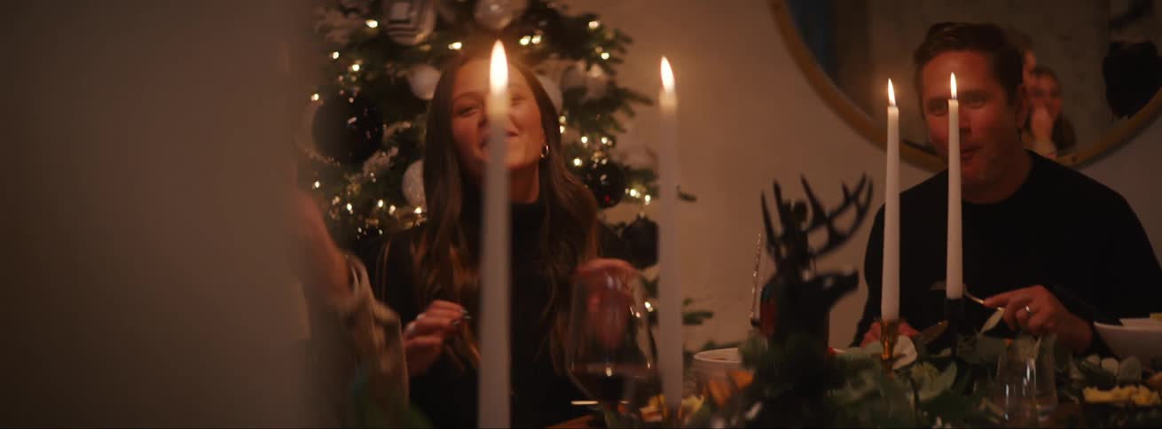 People eating talking and smiling at the dinner table with lighted candles at night