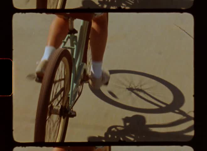 Female wearing short rides bike down concrete path during the day