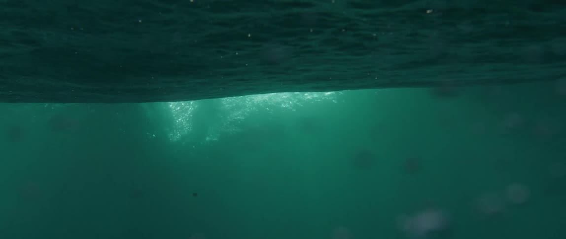 View from inside the sea of a person gliding with a surfboard