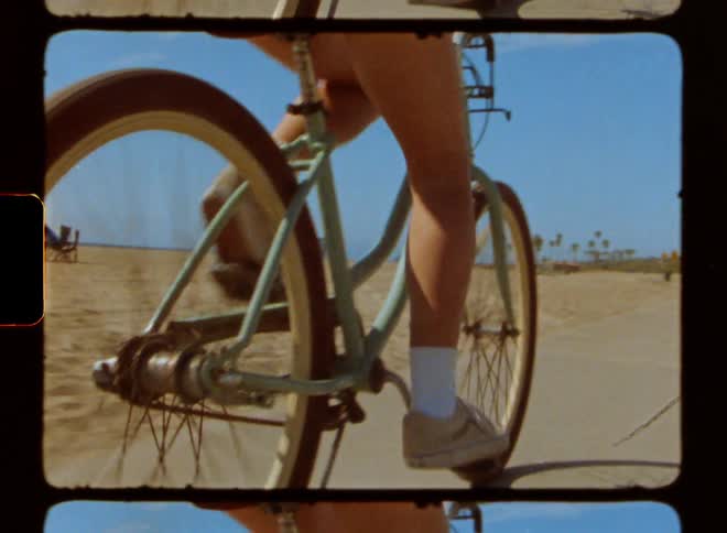Closeup of the wheels of a bicycle in motion on the sidewalk next to the beach