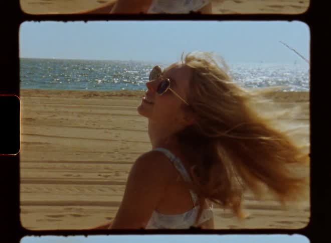 Portrait of a blonde woman riding a bicycle on the beach flipping her hair