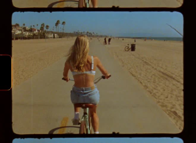 Woman cycling on a track in the middle of the beach her back facing the camera