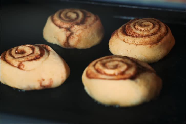 Cinnamon yeast rolls rise and bake in a pan in the oven