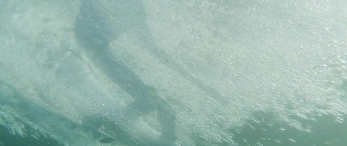 View from inside the sea of a person surfing a wave
