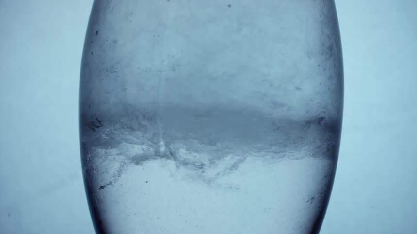 Water drips down side of transparent object containing gas