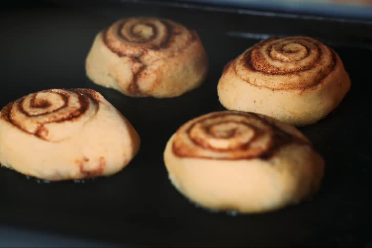 Four sweet cupcakes rising as the batter bakes in the oven