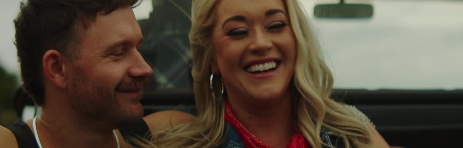 Portrait of a man and a woman inside a car looking at each other and smiling