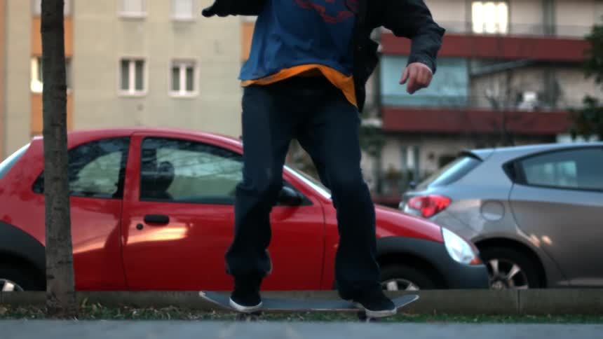 Skateboarder jumps near parked red car