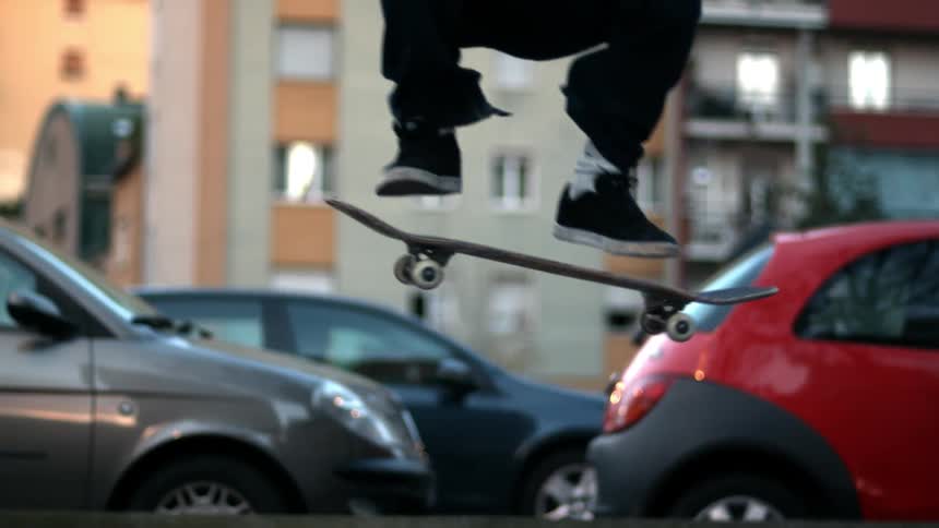 Person performs skateboard stunt on the sidewalk at midday